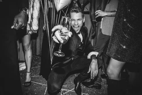 A guest celebrating with a drink at an event afterparty